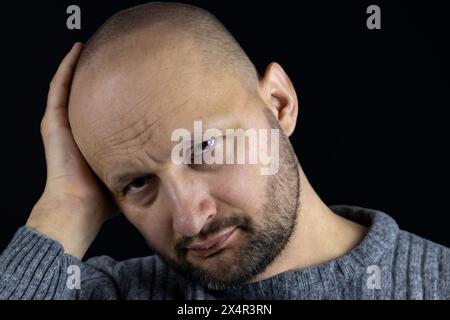 Voici un portrait saisissant d'un homme de 45 ans, profondément dans la pensée, reposant sa tête sur sa main et regardant attentivement la caméra. Banque D'Images