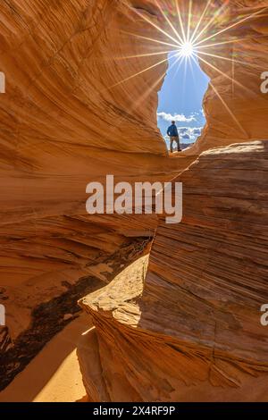 Randonneur debout à Melody Arch avec rafale de soleil à Marble Canyon près de The Wave, Coyote Buttes North, Vermilion Cliffs National Monument, Arizona, États-Unis Banque D'Images