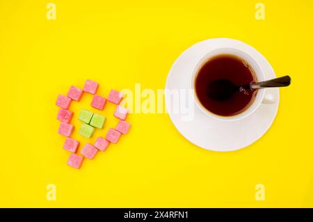 tasse de thé chaud et morceaux de sucre isolé sur jaune Banque D'Images