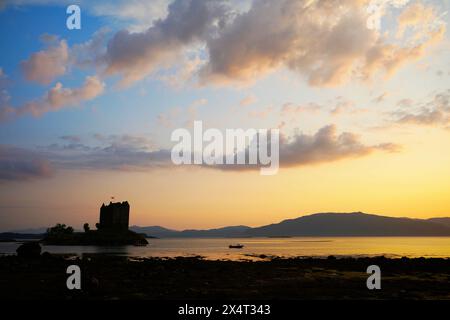 Château Stalker, occupant un îlot dans le Loch Laich, un lac de mer qui s'ouvre dans le Loch Linnhe, alors que le soleil plongeait sous les collines au-delà. Banque D'Images