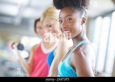 Femme, sourire et portrait pour l'entraînement dans la salle de gym pour la forme physique, la classe et la croissance musculaire. Fille, heureuse et confiante pour l'exercice dans le centre d'athlète pour Banque D'Images