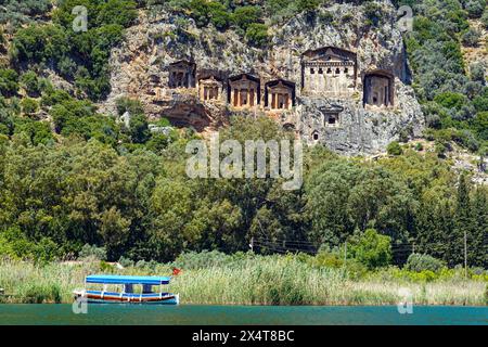 Bateaux fluviaux touristiques et tombes royales lyciennes sculptées dans la paroi rocheuse, à la destination touristique populaire de Dalyan, province de Mugla, Turquie Banque D'Images