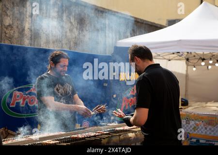 Barbecue en plein air avec des hommes grillant de la viande Banque D'Images