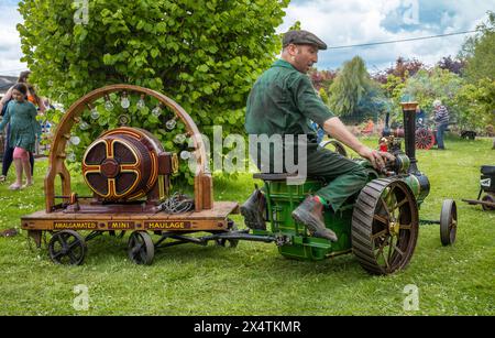 Un passionné conduit un moteur de traction miniature à vapeur tirant une remorque avec une dynamo électrique au South Downs Steam Railway, Pulborough, Wes Banque D'Images