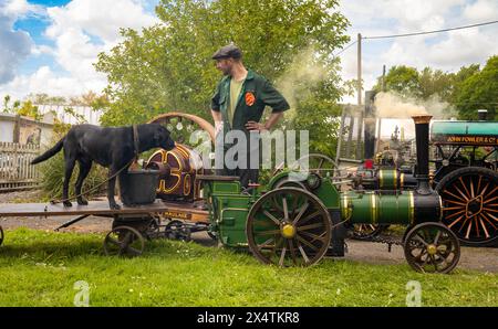 Un passionné de vapeur avec son chien labrador noir et son moteur de traction miniature à vapeur au South Downs Steam Railway, Pulborough, West Su Banque D'Images