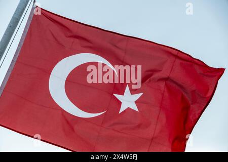 Un drapeau turc agitant au vent contre un ciel bleu clair, symbolisant la fierté nationale, la liberté et la culture dynamique de la Turquie Banque D'Images