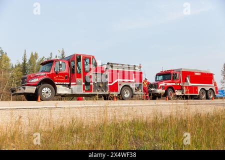 Camions de pompiers de Hay River le long de la route lors d'un feu de forêt dans les Territoires du Nord-Ouest, Canada. Plus de 4 millions d'hectares de forêt brûlés au cours de la saison 2023. Banque D'Images