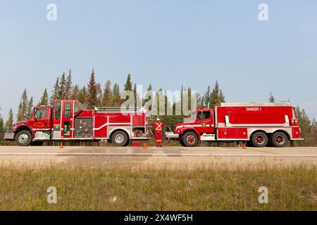 Camions de pompiers de Hay River le long de la route lors d'un feu de forêt dans les Territoires du Nord-Ouest, Canada. Plus de 4 millions d'hectares de forêt brûlés au cours de la saison 2023. Banque D'Images