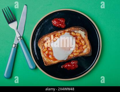 Haricots sur pain grillé avec un œuf poché sur fond vert. Banque D'Images