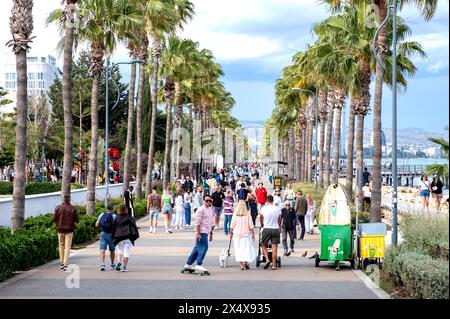 Foules de gens marchant le long de la promenade bordée de palmiers, Limassol, Chypre Banque D'Images