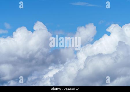 Le ciel bleu électrique est orné de nuages de cumulus blancs moelleux, créant un paysage pittoresque avec des avions volant dans l'atmosphère Banque D'Images