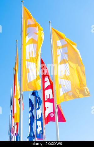 PRAGUE, TCHÉQUIE -AVRIL, 2024 : couleurs différentes drapeaux IKEA contre le ciel bleu. Banque D'Images