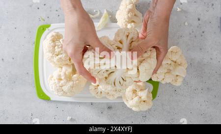 Le chef a dévié le chou-fleur en bouquets, le processus de cuisson, vue d'en haut. Recette de chou-fleur rôti au four. Banque D'Images