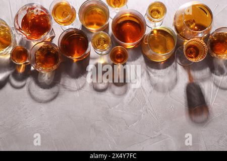 Beaucoup de liqueurs différentes dans des verres sur table texturée grise, pose à plat. Espace pour le texte Banque D'Images