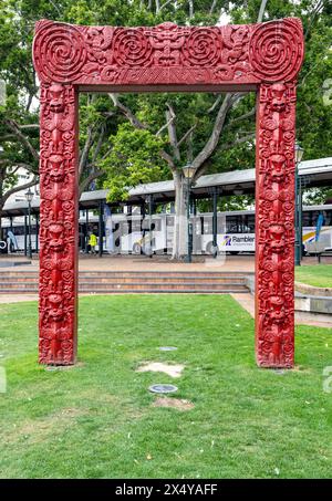 Dunedin, Nouvelle-Zélande - 9 septembre 2023 : une passerelle maorie sculptée, ou waharoa, avec des motifs rouges traditionnels, située dans l'Octogone. Banque D'Images