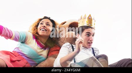 L'image capture un moment amusant avec une jeune femme et un homme vêtus d'une tenue décontractée, entourés de jouets et de ballons, jouant joyeusement Banque D'Images