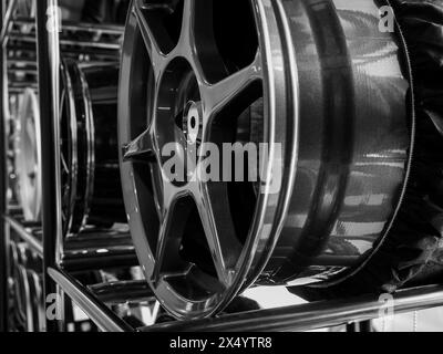 Gros plan décoration de jante de roues en alliage sur étagère en métal dans le fond de magasin de pneus. Photographie en noir et blanc de roue mag chromée haute performance auto PA Banque D'Images