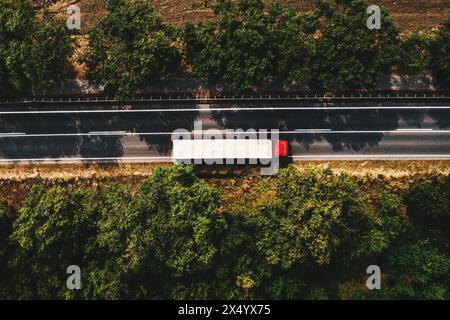 Concept de camionnage et de transport de marchandises, vue aérienne du semi-camion rouge avec remorque blanche sur la route, directement au-dessus Banque D'Images