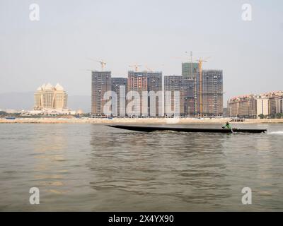 Van Pak Len, Laos - 28 mars 2024 : un navire passe devant des bâtiments résidentiels sous Construccion et le casino Kings Romans (à gauche) sur la rivière Mekon. Banque D'Images