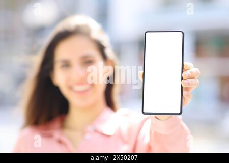 Femme heureuse élégante tenant et montrant la maquette d'écran de téléphone dans la rue Banque D'Images