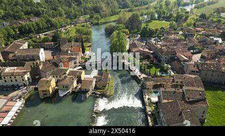 Beau village sur la rive de la rivière vue aérienne du village moulin de Borghetto sul Mincio dans le sud du lac de Garde, en Vénétie, Italie. Drone Banque D'Images