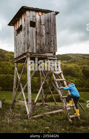 Garçon sur l'échelle de chasse aveugle pendant leur promenade dans la forêt, grimpant pour observer la belle nature printanière, la faune. Banque D'Images