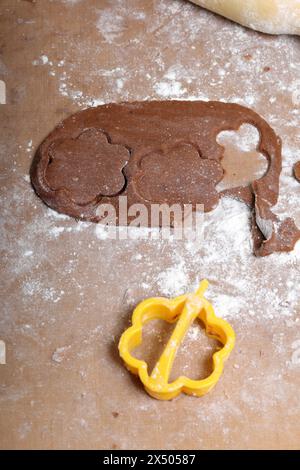 Une femme forme un pain d'épices en utilisant un moule en plastique sur une pâte roulée. La surface de travail est en farine, les outils se trouvent à côté. Cuisson du pain d'épices. Banque D'Images