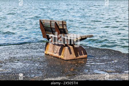 L'odeur de solitude quand la mer se lève, un banc public fait de béton et de bois, chaise en bois sur la plage Banque D'Images