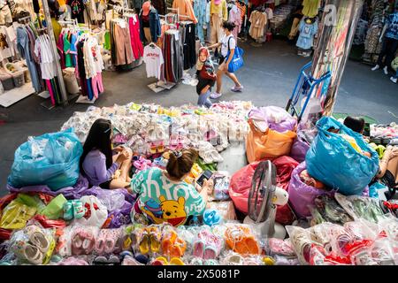 Les porte-étals du marché se trouvent parmi les vêtements et les produits en vente au marché de Pratunam. Bangkok Thaïlande. Banque D'Images