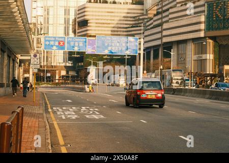 Au cœur de la métropole animée, un taxi court le long des rues animées de Hong Kong, capturant l'énergie dynamique de la ville Banque D'Images