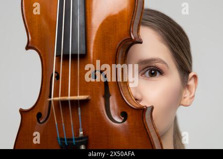 Gros plan d'une jeune femme cachant son visage avec du violon Banque D'Images