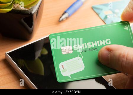 Smishing (SMS message phishing) concept : un homme tient une carte de crédit sur un smartphone Banque D'Images
