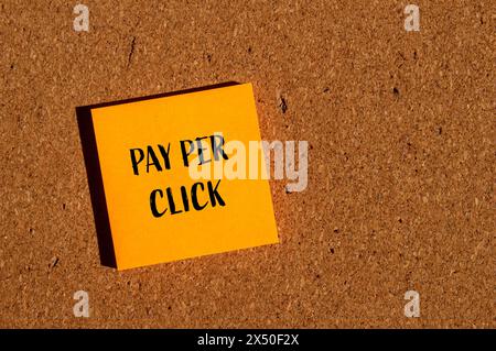 Payer par clic mots écrits sur un autocollant de papier orange avec fond brun. Symbole conceptuel de paiement par clic. Copier l'espace. Banque D'Images