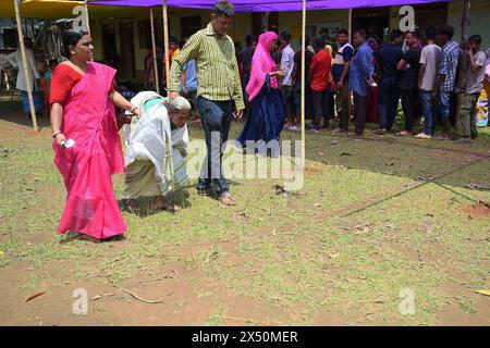 Des bénévoles aident une dame âgée après avoir voté dans la première phase des élections de Lok Sabha dans un bureau de vote de Sonamura à Agartala. Tripura, Inde. Banque D'Images