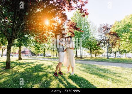 Portrait d'une jeune famille avec leur bébé de neuf mois s'amusant au parc public Banque D'Images