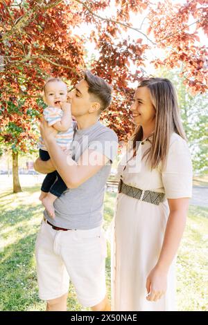 Portrait d'une jeune famille avec leur bébé de neuf mois s'amusant au parc public Banque D'Images