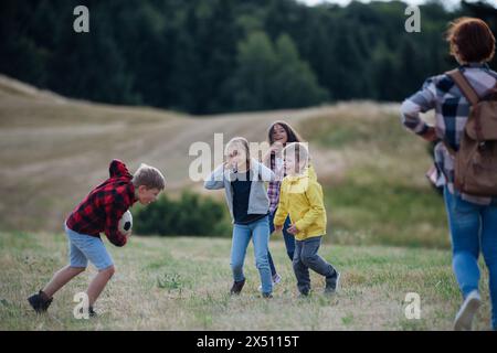 Jeunes élèves jouant avec le professeur en plein air, dans la nature, pendant la classe d'enseignement sur le terrain, courir avec le ballon. Enseignants dévoués pendant l'activité en plein air Banque D'Images