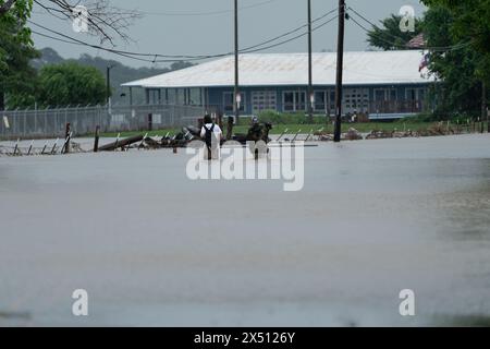 (240506) -- HOUSTON, 6 mai 2024 (Xinhua) -- des personnes portant leur chien pataugeaient sur une route goudronnée à Channelview, à l'est de Houston, Texas, États-Unis, 5 mai, 2024. au moins un garçon a été tué et une femme blessée dimanche dans les eaux de crue au Texas, où plus d'un tiers des comtés ont publié des déclarations de catastrophe au cours de la semaine écoulée en raison des fortes pluies qui continuent de frapper l'État. (Photo de Chen Chen/Xinhua) Banque D'Images