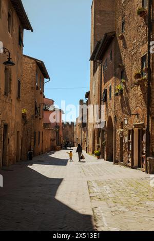 Deux personnes marchant dans la rue principale dans la vieille ville de Certaldo - Certaldo Alto - en Toscane, Italie. Pris sur une journée ensoleillée d'avril avec un ciel lumineux. Banque D'Images