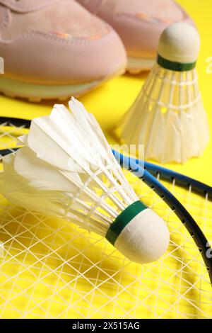 Volants de badminton en plume, raquettes et baskets sur fond jaune, gros plan Banque D'Images