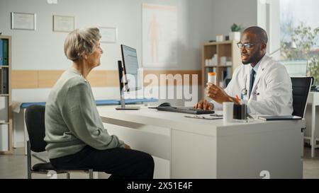 Médecin de famille afro-américain prescrit des médicaments à la patiente senior et parle avec elle pendant la consultation dans une clinique de santé. Médecin assis derrière un bureau dans le bureau de l'hôpital. Banque D'Images