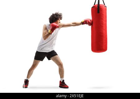 Jeune homme frappant un sac de boxe isolé sur fond blanc Banque D'Images