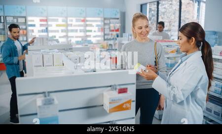 En pharmacie Drugstore Groupe diversifié de clients multi-ethniques naviguant en médecine. Pharmacien professionnel parle avec la cliente féminine, recommande des produits de soins de santé, suppléments, médicaments Banque D'Images