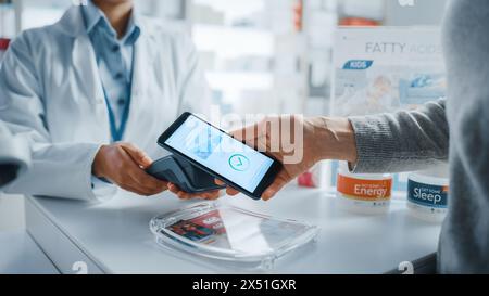 Pharmacie Drugstore Checkout comptoir caissier : pharmacien et un client utilisant le smartphone NFC avec terminal de paiement sans contact pour acheter des médicaments sur ordonnance, des produits de soins de santé. Gros plan Banque D'Images