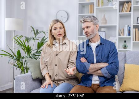 Couple d'âge moyen engagé dans une consultation sérieuse en ligne avec un psychologue de famille, exprimant des préoccupations et cherchant des conseils. Banque D'Images