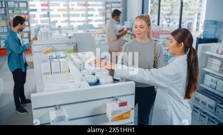 En pharmacie Drugstore Groupe diversifié de clients multi-ethniques naviguant en médecine. Pharmacien professionnel parle avec la cliente féminine, recommande des produits de soins de santé, suppléments, médicaments Banque D'Images