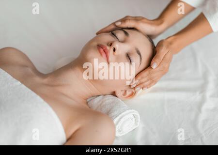 Jeune femme blonde se relaxant pendant le massage facial au spa Banque D'Images