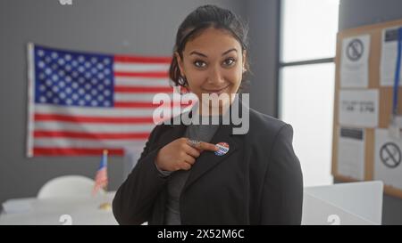 Jeune femme hispanique montrant l'autocollant « j'ai voté » à l'intérieur avec le drapeau américain en toile de fond, évoquant le devoir civique et la fierté. Banque D'Images