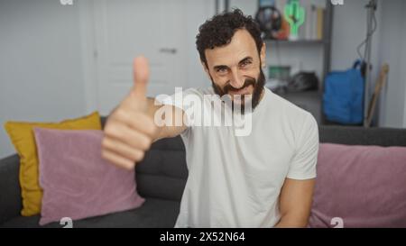 Homme barbu dans le salon donnant les pouces Banque D'Images