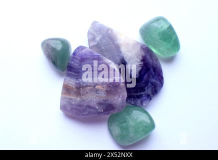 Des sections de belles pierres de fluorite violette rayées et de fluorite verte se rapprochent sur un fond blanc. Cristaux de Chakra de guérison Banque D'Images